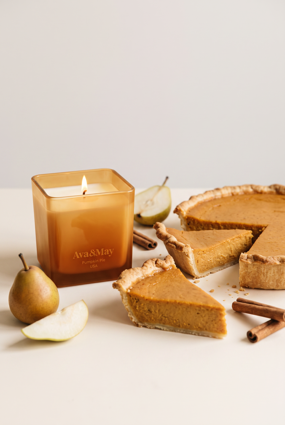 Bougie Pumpkin Pie 220 g d'Ava&May allumée, avec une tarte à la citrouille, aux poires et à la cannelle
